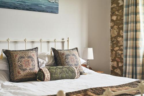 a bedroom with a bed with pillows on it at Half Moon Cottage in Stockland