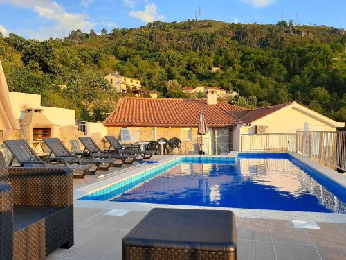 a swimming pool with lounge chairs next to a house at Casa do Quitaranda - Gerês in Vieira do Minho