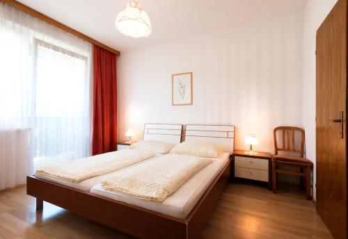 a bedroom with a large bed and a window at Appartements Kanauf in Krumpendorf am Wörthersee