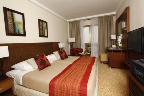a hotel room with a large bed and a television at Hala Hotel & Aqua Park in Bissau