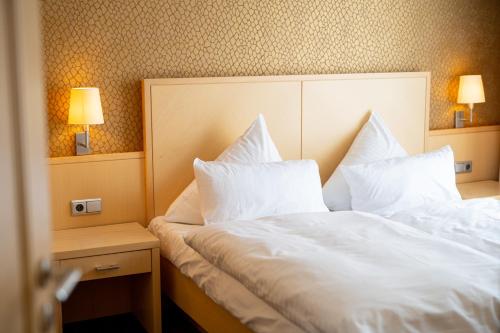 a hotel room with a bed with white sheets and pillows at Landhaus Bergkrone in Willingen