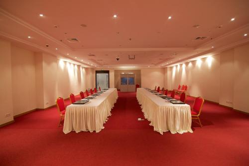 a conference room with long tables and red chairs at Hala Hotel & Aqua Park in Bissau