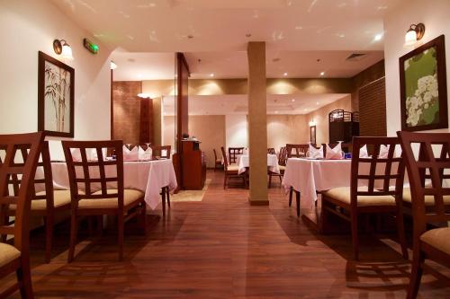 a dining room with white tables and chairs at Hala Hotel & Aqua Park in Bissau