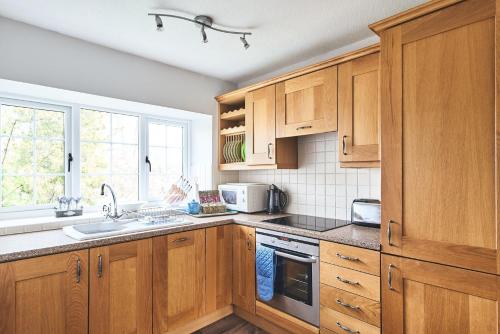 a kitchen with wooden cabinets and a sink at Tree Pipit Cottage in Stockland