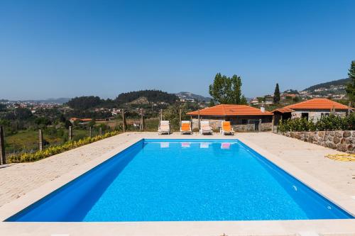 a blue swimming pool with two chairs and a house at Partezins III in Castelo de Paiva