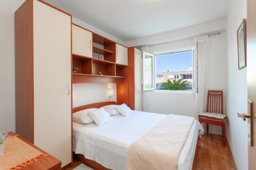 a bedroom with a white bed and a window at Apartman Vlahović in Makarska