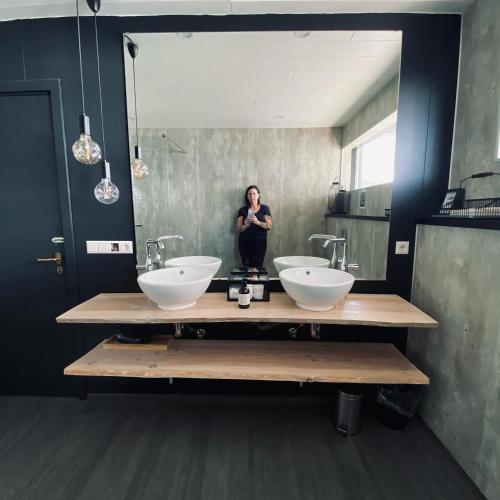 a woman standing in front of a mirror in a bathroom at Guesthouse Stekkaból in Patreksfjörður