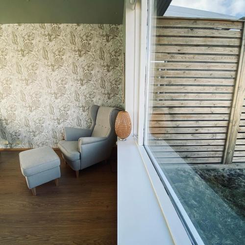 a room with a chair and a window with blinds at Guesthouse Stekkaból in Patreksfjörður