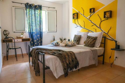 a bedroom with a bed with a yellow wall at L'île au paon - Appartement T2 avec piscine et parking in Les Abymes