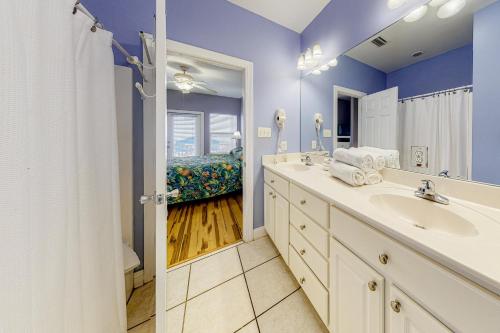 La salle de bains est pourvue d'un lavabo et d'un grand miroir. dans l'établissement Purple House, à Gulf Shores