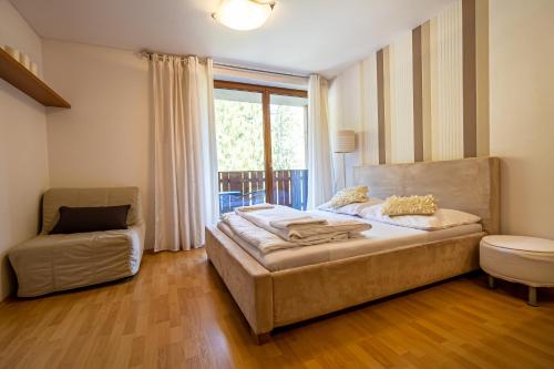 a bedroom with a bed and a chair and a window at Fatrapark 2 Apartments HRABOVO - Hlavná recepcia in Ružomberok