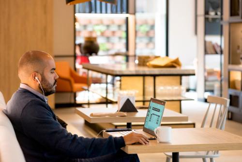 a man with a headset sitting at a table with a laptop at Lettera Hotel in Medellín