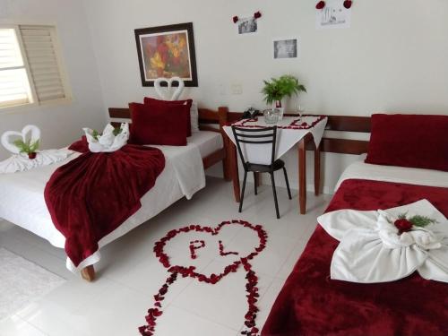 - une chambre avec 2 lits et une table à la décoration cardiaque dans l'établissement Hotel Do Lago, à Guaíra