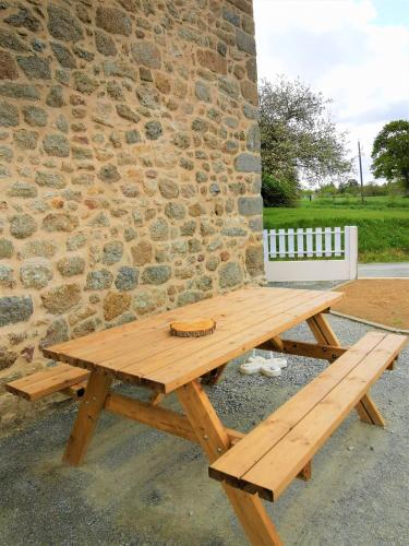 a wooden picnic table in front of a brick wall at Gîte Ty coz'y in Québriac
