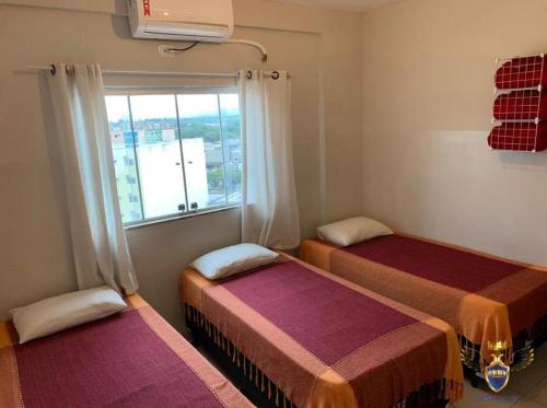 2 Betten in einem Zimmer mit Fenster in der Unterkunft Golden Apart Hotel in Aparecida