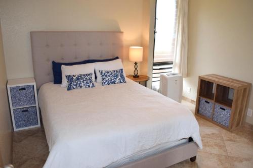 1 dormitorio con 1 cama blanca grande con almohadas azules en Beautiful Private Condo Walking Distance to Beach MV2321, en Kihei