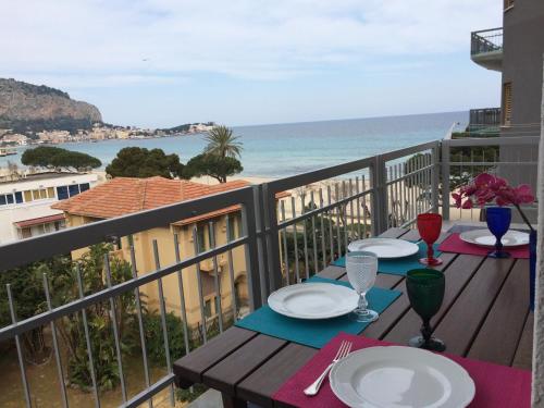 a table on a balcony with a view of the ocean at Mondello Luxury Apartment on the Beach in Mondello