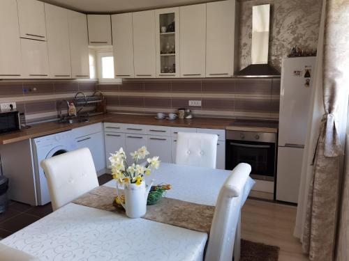 uma cozinha com armários brancos e uma mesa com flores em Nikolaj Lux em Nova Varos
