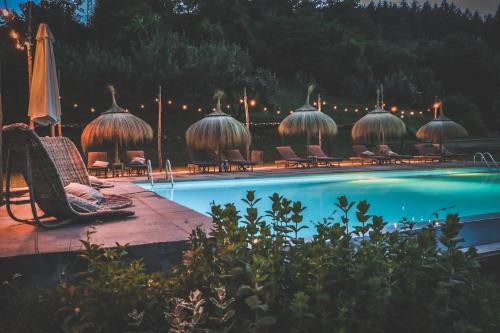 una piscina con sedie e ombrelloni accanto a una piscina di Agriturismo Rancone Lodges a Camporgiano