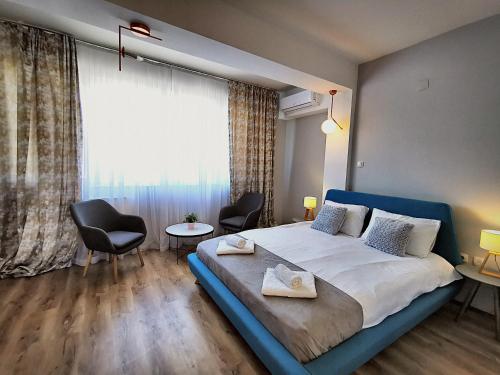 a bedroom with a large bed with two chairs and a window at Guest rooms Denicija in Skopje