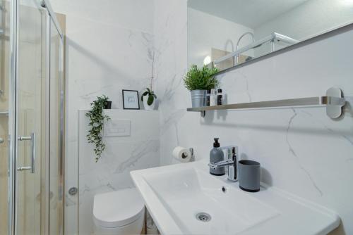 a white bathroom with a sink and a toilet at Josipa & Jelena Apartment in Senj