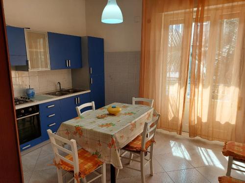 una cocina con armarios azules y una mesa con sillas en Ventura CasaVacanze, en Oliveri