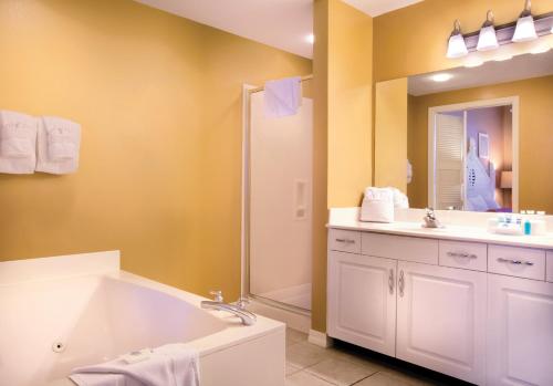 a bathroom with a tub and a sink and a mirror at Club Wyndham at Majestic Sun in Destin