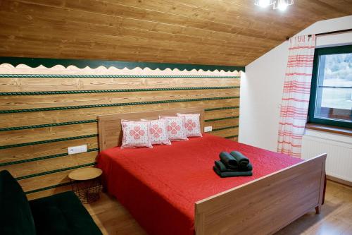 a bedroom with a red bed with a wooden wall at Apartmán Elenka in Zuberec