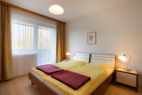 ein Schlafzimmer mit einem Bett mit gelber Bettwäsche und einem Fenster in der Unterkunft Appartements Kanauf in Krumpendorf am Wörthersee
