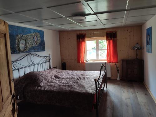 Schlafzimmer mit einem Bett und einem Fenster mit roten Vorhängen in der Unterkunft Allgäu Apartment Rose im OG in Grünenbach