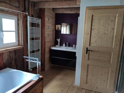 a bathroom with a wooden door and a sink at Allgäu Apartment Rose im OG in Grünenbach