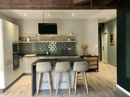 - une cuisine avec un comptoir avec deux tabourets et une cuisinière dans l'établissement Superbe appartement cosy au coeur du beaujolais, à Odenas