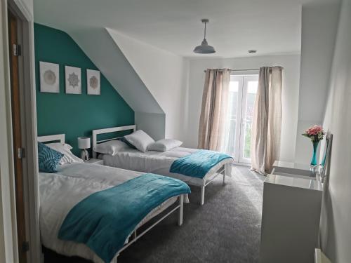 a bedroom with two beds and a blue wall at Spacious & modern 3 Bed Apartment + parking & central location in Wakefield