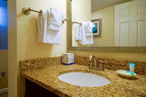 a bathroom with a sink and a mirror and towels at La Costa Beach Club by Capital Vacations in Pompano Beach