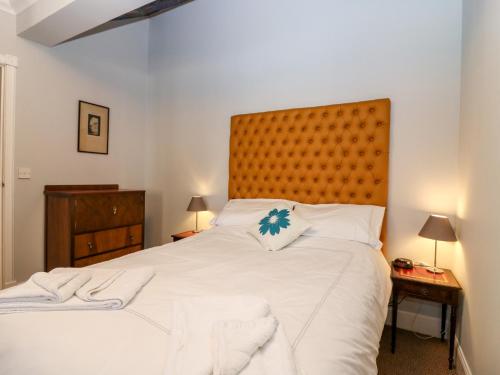 a bedroom with a large white bed with a wooden headboard at Courtyard Cottage in Letham