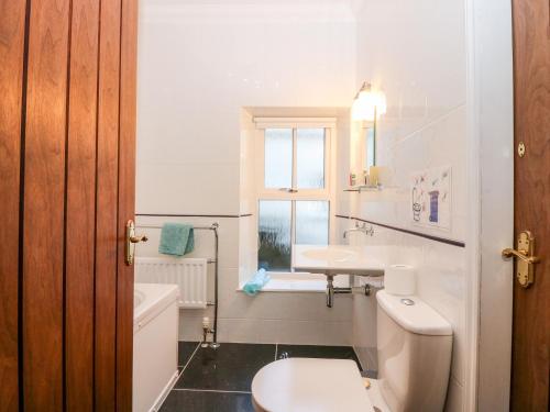 a white bathroom with a sink and a toilet at Courtyard Cottage in Letham