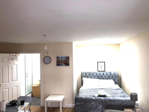 1 dormitorio con 1 cama y reloj en la pared en Lt Properties studio apartment Ground floor 1 en Luton