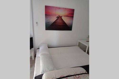 białe łóżko w pokoju ze zdjęciem na ścianie w obiekcie Jupiter Beach Estudio w mieście Benalmádena