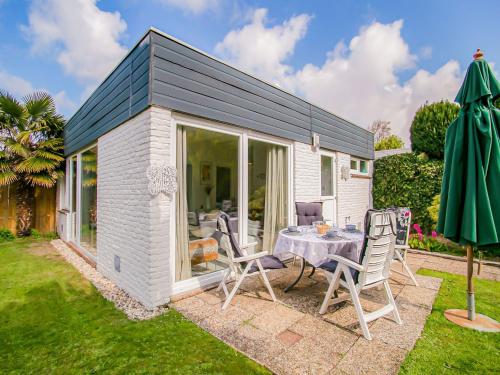 een kleine witte schuur met een tafel en stoelen bij Lovely Bungalow in Noordwijkerhout with Garden in Noordwijkerhout