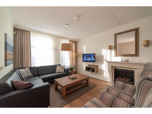 een woonkamer met een bank en een open haard bij Holiday home with whirlpool quiet area in Zeeland in Colijnsplaat
