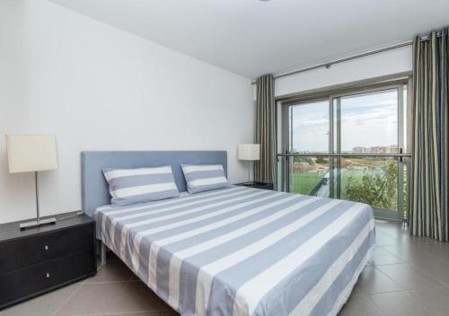 een slaapkamer met een groot bed en een groot raam bij Praia da Rocha Apartments in Portimão