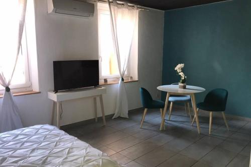 Schlafzimmer mit einem Bett, einem Tisch und einem TV in der Unterkunft Studio cocooning à 50 m du port in Cassis
