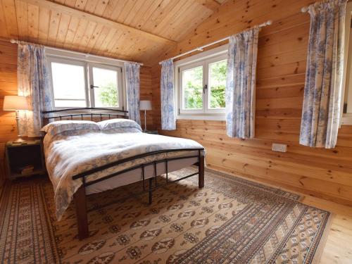 a bedroom with a bed and two windows at Mill Cabin Denant in Haverfordwest