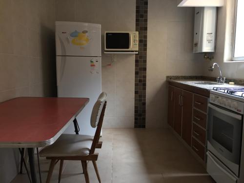 Miramar - Depto 2 ambientes في ميرامار: مطبخ مع طاولة وثلاجة بيضاء
