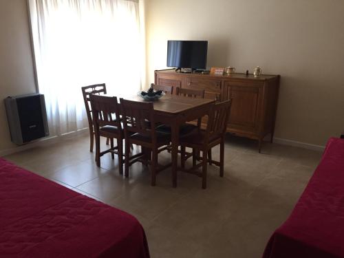 Miramar - Depto 2 ambientes في ميرامار: غرفة طعام مع طاولة وكراسي وتلفزيون