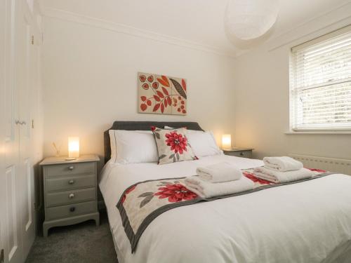 - une chambre avec un lit blanc et des serviettes dans l'établissement Riverside Cottage, à Cockermouth