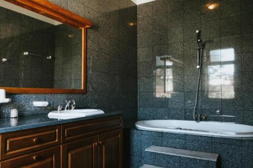 y baño con bañera, lavabo y espejo. en Casa dos Vales - Luxury Villa en Penafiel