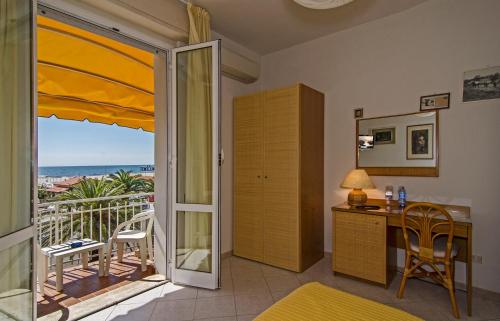 マリーナ・ディ・ピエトラサンタにあるHotel Alkのデスク、海を望むバルコニーが備わる客室です。