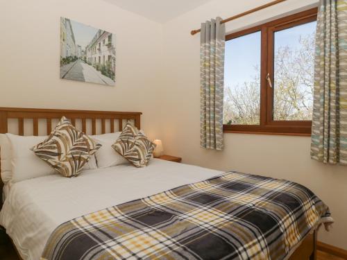a bedroom with a bed with pillows and a window at Cherry Lodge in Watchet