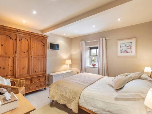 a bedroom with a large bed and a wooden cabinet at Riverstone Cottage in Skipton